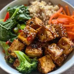 ['Close-up view of a vibrant Buddha bowl featuring crispy tofu, colorful vegetables, and quinoa.', 'Side view of an air fryer tofu Buddha bowl with broccoli, carrots, red bell pepper, and spinach.', 'Juicy Buddha bowl filled with tofu, quinoa, and a variety of fresh veggies, captured with an iPhone.', 'Delicious assortment of ingredients in a Buddha bowl, highlighting tofu and sautéed greens.']