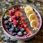 A close-up side view of a vibrant berry detox smoothie bowl with colorful toppings.