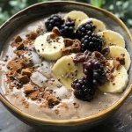 Close-up view of a gingerbread smoothie bowl topped with blackberries and gingerbread almond butter.