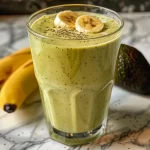 Close-up side view of a creamy avocado banana smoothie in a glass.