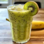 Close-up of a creamy banana kiwi smoothie in a glass, with fruit slices nearby.
