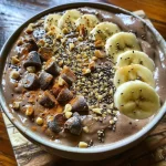 Close-up of a creamy cacao banana smoothie bowl garnished with fresh fruit.