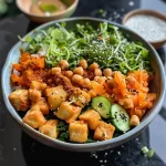 A vibrant Buddha bowl filled with coral lentils, sweet potatoes, and colorful vegetables.