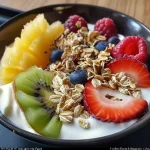 A colorful yaourt bowl filled with Greek yogurt, fresh fruit, muesli, and seeds.